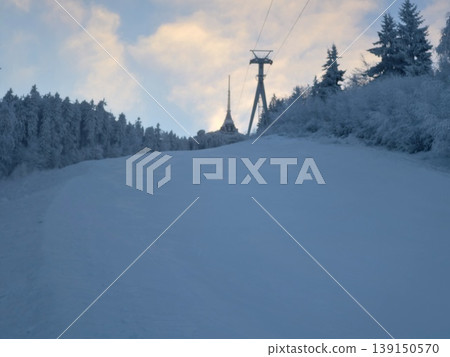 Mountain slope with frosted trees. Calm winter scene featuring groomed trail and snowy pine forest 139150570