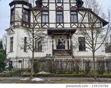 Old mansion with garden surroundings. Grand historic villa featuring ornate facades and winter scenery Old mansion with garden surroundings. Grand historic villa featuring ornate facades and winter scenery 139150766