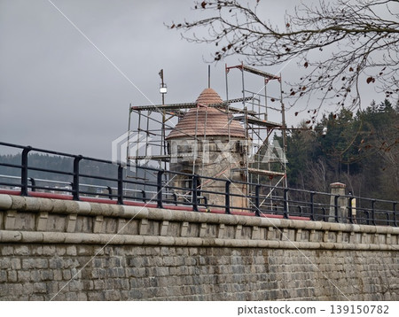 Ancient masonry being repaired near water. Renovation of historic damside stonework with scaffolding Ancient masonry being repaired near water. Renovation of historic damside stonework with scaffolding 139150782