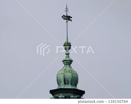 Copper finial with weather vane. Architectural feature with weather vane and decorative finial contrast 139150784
