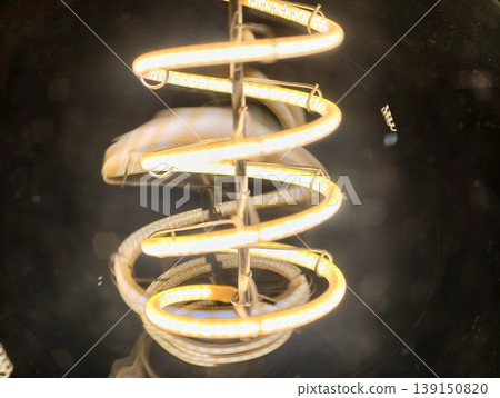 Precious vintage lighting highlighting glowing spiral filament encased in transparent glass with reflections Precious vintage lighting highlighting glowing spiral filament encased in transparent glass with reflections 139150820