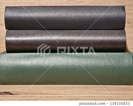 Multiple rolls of textured vinyl displayed on wooden surface suitable for renovation needs 139150833