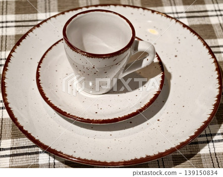 Vintage dishware on plaid table. Farmhouse table featuring speckled dishware and cozy rustic textures 139150834