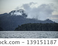 Serene landscape of mountains and a lake under early morning fog. 139151187