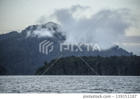 Serene landscape of mountains and a lake under early morning fog. Serene landscape of mountains and a lake under early morning fog. 139151187