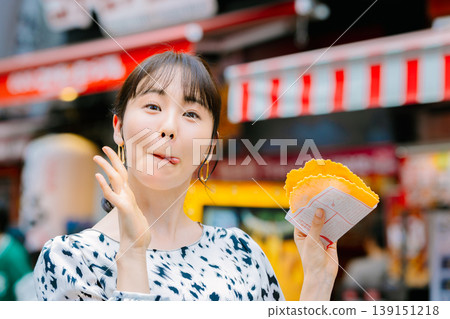 A woman eating the famous takosen in Dotonbori, Osaka A woman eating the famous takosen in Dotonbori, Osaka 139151218