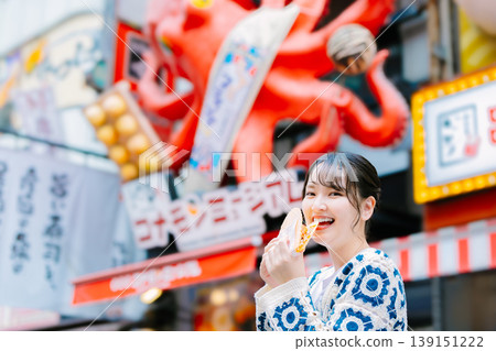 A woman eating the famous takosen in Dotonbori, Osaka A woman eating the famous takosen in Dotonbori, Osaka 139151222
