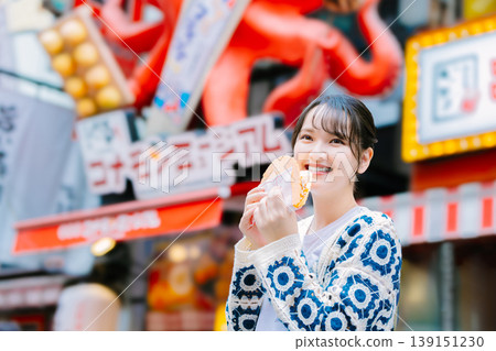 一位女士在大阪道頓堀吃著名的章魚線 一位女士在大阪道頓堀吃著名的章魚線 139151230