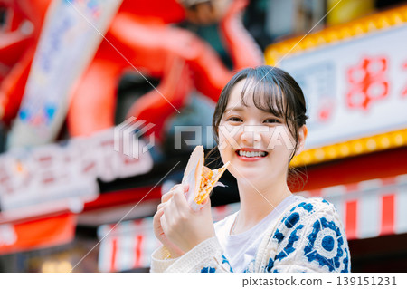 A woman eating the famous takosen in Dotonbori, Osaka A woman eating the famous takosen in Dotonbori, Osaka 139151231