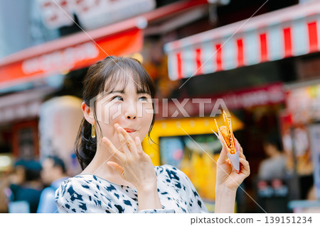 一位女士在大阪道頓堀吃著名的章魚線 139151234