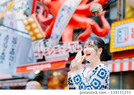 一位女士在大阪道頓堀吃著名的章魚線 一位女士在大阪道頓堀吃著名的章魚線 139151255