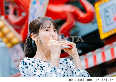一位女士在大阪道頓堀吃著名的章魚線 139151257