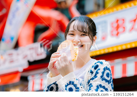 A woman eating the famous takosen in Dotonbori, Osaka A woman eating the famous takosen in Dotonbori, Osaka 139151264