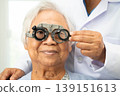Optometrist checking Asian elderly woman ophthalmic vision eye test and using optical trial frame. 139151613