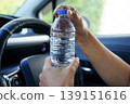 Asian woman driver holding water bottle in car. 139151616