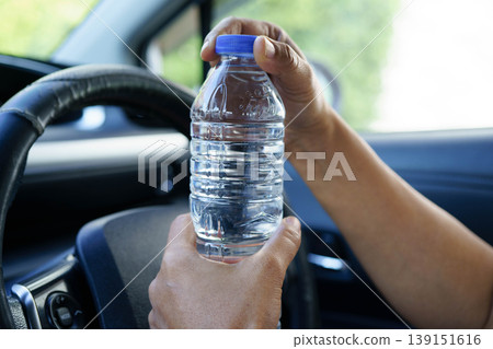 Asian woman driver holding water bottle in car. 139151616