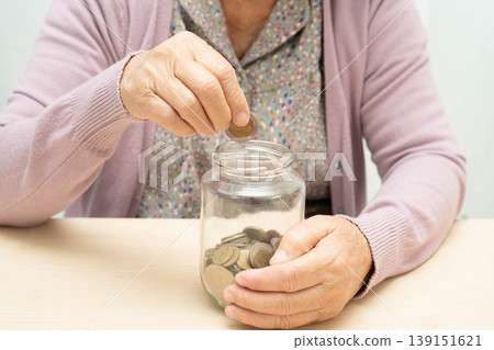 Retired elderly woman putting coins money in piggy bank and worry about monthly expenses and treatment fee payment. 139151621
