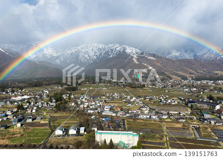 A beautiful rainbow over Hakuba Village and the snow-capped Happo-one ridge, Nagano Prefecture (aerial photograph taken by drone). A beautiful rainbow over Hakuba Village and the snow-capped Happo-one ridge, Nagano Prefecture (aerial photograph taken by drone). 139151763