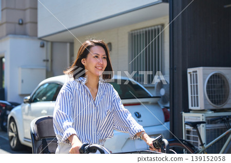 在陽光明媚的日子裡,一位日本女子微笑著騎著腳踏車。 在陽光明媚的日子裡,一位日本女子微笑著騎著腳踏車。 139152058