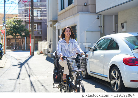 在陽光明媚的日子裡，一位日本女子微笑著騎著腳踏車。 139152064