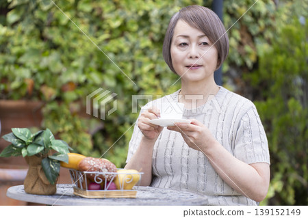 一位老婦人在露臺上喝咖啡 一位老婦人在露臺上喝咖啡 139152149