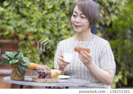 一位老婦人在露臺上喝咖啡 一位老婦人在露臺上喝咖啡 139152161