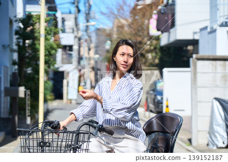 在陽光明媚的日子裡,一位日本女子微笑著騎著腳踏車。 在陽光明媚的日子裡,一位日本女子微笑著騎著腳踏車。 139152187