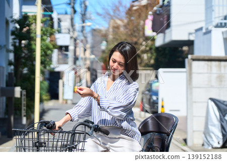 在陽光明媚的日子裡，一位日本女子微笑著騎著腳踏車。 139152188