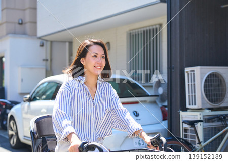 A Japanese woman riding a bicycle with a smile on a sunny day. A Japanese woman riding a bicycle with a smile on a sunny day. 139152189