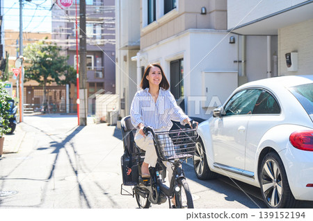 在陽光明媚的日子裡,一位日本女子微笑著騎著腳踏車。 在陽光明媚的日子裡,一位日本女子微笑著騎著腳踏車。 139152194