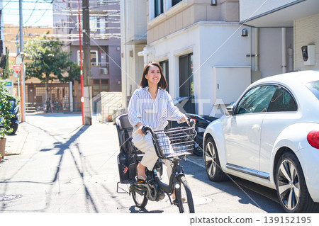 在陽光明媚的日子裡，一位日本女子微笑著騎著腳踏車。 139152195