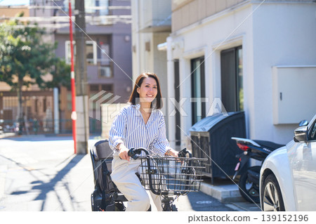 在陽光明媚的日子裡，一位日本女子微笑著騎著腳踏車。 139152196