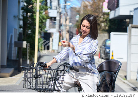 在陽光明媚的日子裡，一位日本女子微笑著騎著腳踏車。 139152197