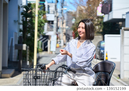 在陽光明媚的日子裡,一位日本女子微笑著騎著腳踏車。 在陽光明媚的日子裡,一位日本女子微笑著騎著腳踏車。 139152199