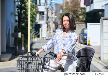 A Japanese woman riding a bicycle with a smile on a sunny day. A Japanese woman riding a bicycle with a smile on a sunny day. 139152503