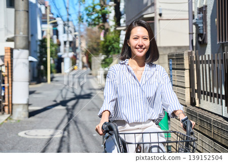 A Japanese woman riding a bicycle with a smile on a sunny day. A Japanese woman riding a bicycle with a smile on a sunny day. 139152504