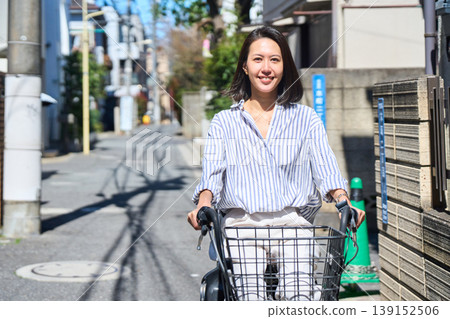 在陽光明媚的日子裡，一位日本女子微笑著騎著腳踏車。 139152506