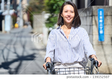 在陽光明媚的日子裡,一位日本女子微笑著騎著腳踏車。 在陽光明媚的日子裡,一位日本女子微笑著騎著腳踏車。 139152507