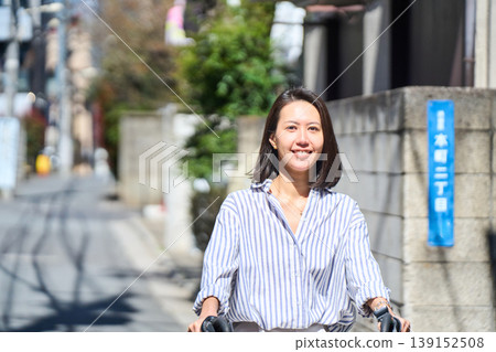在陽光明媚的日子裡,一位日本女子微笑著騎著腳踏車。 在陽光明媚的日子裡,一位日本女子微笑著騎著腳踏車。 139152508