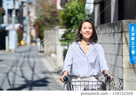 A Japanese woman riding a bicycle with a smile on a sunny day. A Japanese woman riding a bicycle with a smile on a sunny day. 139152509