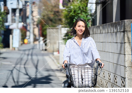 A Japanese woman riding a bicycle with a smile on a sunny day. A Japanese woman riding a bicycle with a smile on a sunny day. 139152510