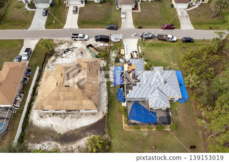Workers covering private house with asphalt shingles. Rooftop installation project in Florida home construction. 139153019