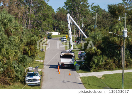 Worker in lift truck trimming tree around power lines. Maintenance of electrical grid by city utility cervices Worker in lift truck trimming tree around power lines. Maintenance of electrical grid by city utility cervices 139153027
