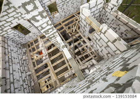 View from above of future multi stored cottage energy saving walls of large white hollow foam insulation blocks and temporary wooden scaffolding frame. Construction masonry, modern technology concept. View from above of future multi stored cottage energy saving walls of large white hollow foam insulation blocks and temporary wooden scaffolding frame. Construction masonry, modern technology concept. 139153084