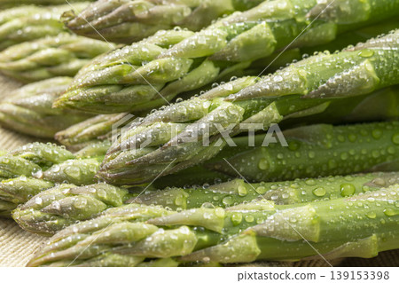 A photograph of spring vegetables, with fresh green asparagus arranged and glistening with water droplets. A photograph of spring vegetables, with fresh green asparagus arranged and glistening with water droplets. 139153398