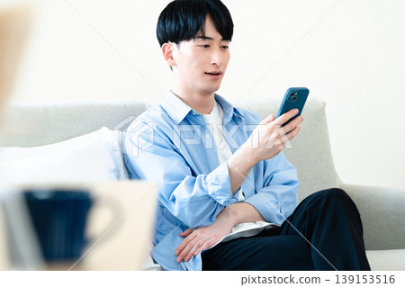 一個在客廳裡使用智能手機的人 139153516