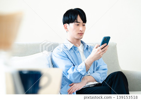 一個在客廳裡使用智能手機的人 139153518