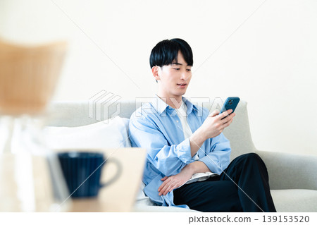 一個在客廳裡使用智能手機的人 139153520