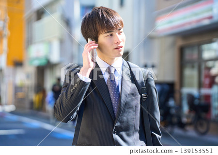 一位年輕的日本商人外出拜訪客戶時，在街上接了電話。 139153551