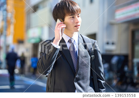 一位年輕的日本商人外出拜訪客戶時,在街上接了電話。 一位年輕的日本商人外出拜訪客戶時,在街上接了電話。 139153558